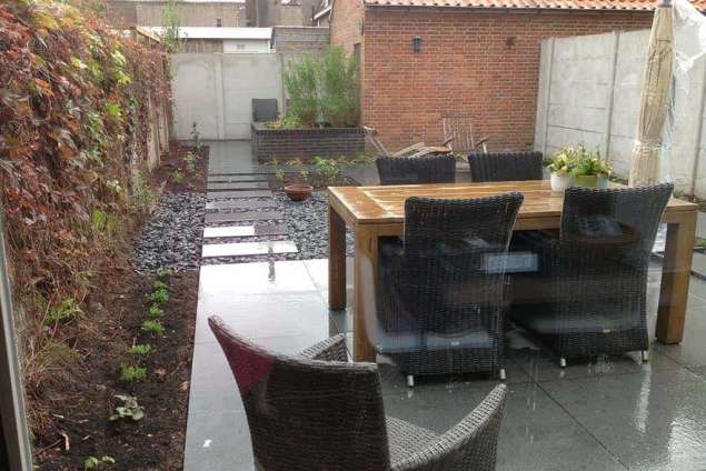 Leggen van 80x80x3 natuursteen in een achtertuin. de stoep wordt ingeveegd met proxizand <gatewayzand>
